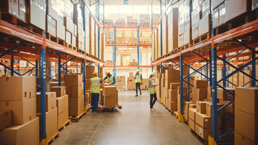 warehouse full of boxes with workers sorting the packages